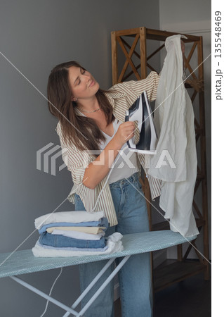 Home organization and work day preparation brunette ironing clothes holding iron creating neatness and order Home organization and work day preparation brunette ironing clothes holding iron creating neatness and order 135548469