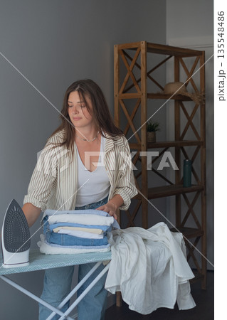 Woman doing home dry cleaning steaming clothes with an iron for a flawless neat and well cared for appearance 135548486