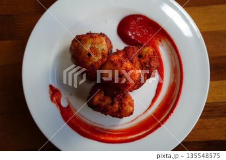 Spicy Fried Chicken Bites with Red Chili Sauce on a White Plate 135548575