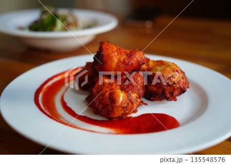 Spicy Fried Chicken Bites with Red Chili Sauce on a White Plate Spicy Fried Chicken Bites with Red Chili Sauce on a White Plate 135548576
