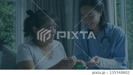 Holding pill bottle, nurse in blue scrubs, stethoscope guiding patient examining cap in living room Holding pill bottle, nurse in blue scrubs, stethoscope guiding patient examining cap in living room 135548602