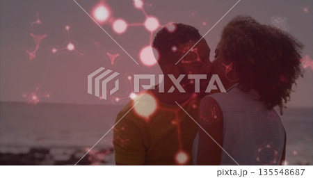 Kissing couple wearing denim vest and yellow T-shirt on rocky beach at sunset, floating red overlay Kissing couple wearing denim vest and yellow T-shirt on rocky beach at sunset, floating red overlay 135548687