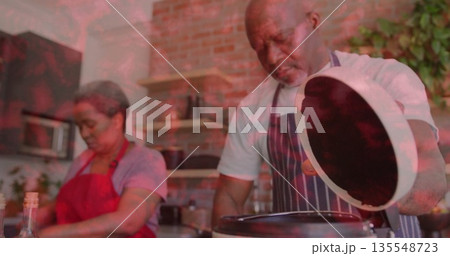 Chopping vegetables on board, woman in red apron prepping in home kitchen, partner lifting pot lid Chopping vegetables on board, woman in red apron prepping in home kitchen, partner lifting pot lid 135548723