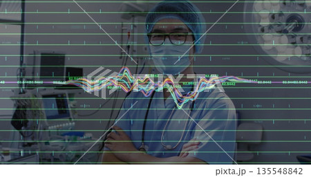 Standing doctor wearing scrubs and mask crossing arms in ICU, with stethoscope and ECG overlay Standing doctor wearing scrubs and mask crossing arms in ICU, with stethoscope and ECG overlay 135548842