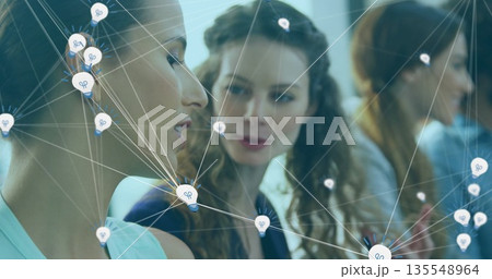 Mid adult woman wearing dark blazer speaking in office meeting, with lightbulb icons and lines 135548964