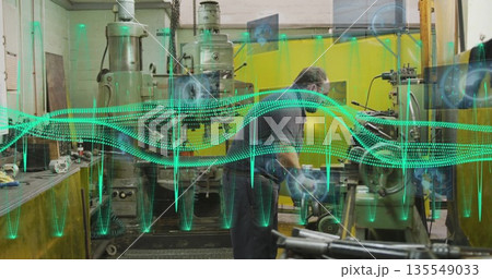 Operating technician adjusting milling machine in machine shop with digital overlays, copy space Operating technician adjusting milling machine in machine shop with digital overlays, copy space 135549033