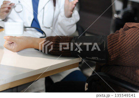 A doctor's hands carefully taking a patient's blood pressure using a sphygmomanometer. 135549141