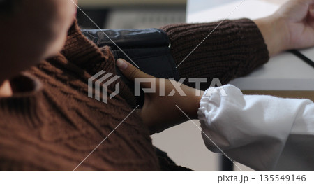 A doctor's hands carefully taking a patient's blood pressure using a sphygmomanometer. A doctor's hands carefully taking a patient's blood pressure using a sphygmomanometer. 135549146