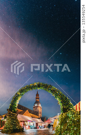 Riga, Latvia. Traditional Christmas Market On Dome Square With Cathedral. Famous Landmark In Winter Evening Night In Festive Illuminations Lighting Riga, Latvia. Traditional Christmas Market On Dome Square With Cathedral. Famous Landmark In Winter Evening Night In Festive Illuminations Lighting 135549254