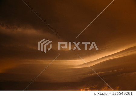 Orange yellow Cloudy Sky With Dark Storm Clouds During Rain. Natural Background With Rainclouds. natural weather background dark yellow backdrop thunderstorm stormy sky 135549261