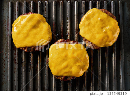 Beef burger patties sizzle and the cheese melts, on a grill, top view. 135549319