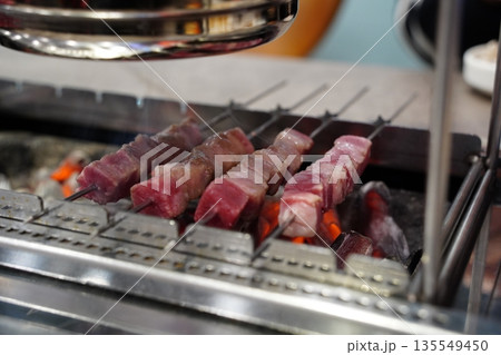 Raw, uncooked lamb skewers on a grill, a popular Chinese barbecue street food, ready for cooking. 135549450