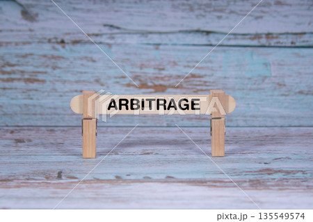 Arbitrage symbol. Single Wooden stick squeezed by Clothespins, Grungy blue Wooden Texture Background. Business and Arbitrage concept with copy space 135549574