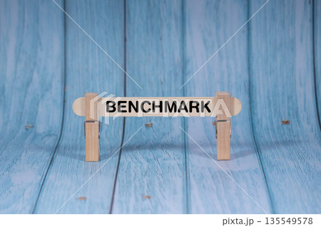 Benchmark symbol. Wooden stick clamped by Clothespins, vivid blue wooden backdrop. Business and Benchmark concept with copy space 135549578