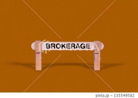 Brokerage symbol. Wooden stick tightened by Clothespins, beautiful Orange color Backdrop. Business and Brokerage concept with copy space Brokerage symbol. Wooden stick tightened by Clothespins, beautiful Orange color Backdrop. Business and Brokerage concept with copy space 135549582
