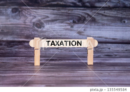 Taxation symbol. A wooden stick secured by Clothespins set over beautiful Realistic Wooden Texture Background. Business and Taxation concept with copy space 135549584