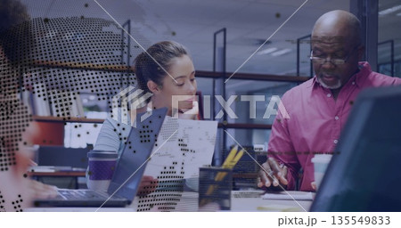 Collaborating colleagues in blue blouse and red shirt using laptop and reports in open-plan office Collaborating colleagues in blue blouse and red shirt using laptop and reports in open-plan office 135549833