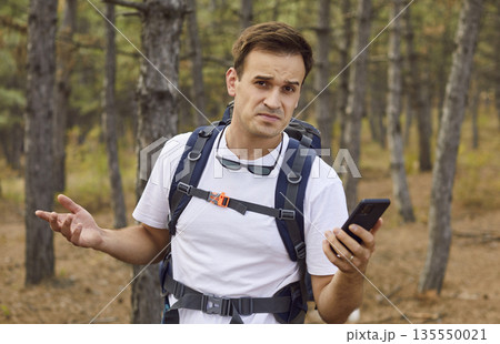 Confused backpacker tourist with smartphone and no signal, lost in forest map 135550021