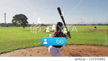 Holding bat batter wearing maroon uniform and black helmet at park, with players in blue jerseys 135550062