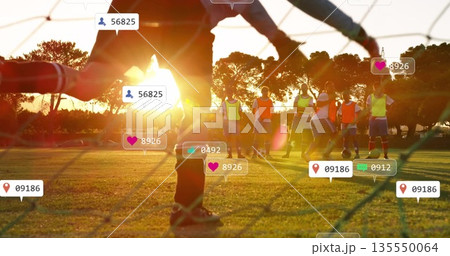 Diving goalkeeper wearing gloves blocking soccer ball at sunset on grass with bibs and social icons 135550064