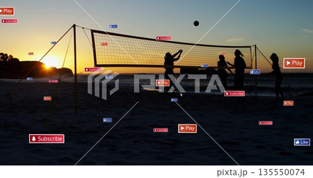 Silhouetted group of five women playing volleyball on sandy beach at sunset, with volleyball net 135550074