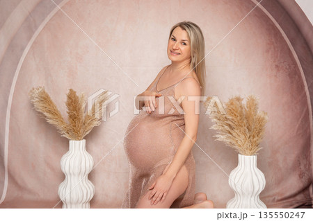 Side view artistic portrait of a nude pregnant woman emphasizing the baby bump. Soft light and minimal decor. Concept of pregnancy beauty and natural femininity 135550247