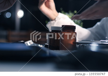 Medical team having a meeting with doctors in white lab coats and surgical scrubs seated at a table discussing a patients working online using computers in the medical industry. 135550747