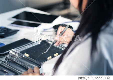 Medical team having a meeting with doctors in white lab coats and surgical scrubs seated at a table discussing a patients working online using computers in the medical industry. 135550748