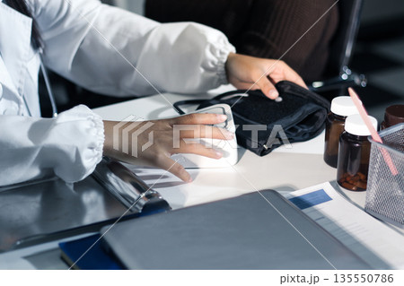 A doctor's hands carefully taking a patient's blood pressure using a sphygmomanometer. 135550786