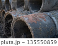 Stacked concrete drainage pipes at outdoor construction site. Urban infrastructure development, civil engineering work, and stormwater management system. Concrete sewer pipe. Municipal infrastructure. 135550859