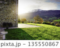 Sunlit countryside landscape with green meadow, stone house terrace, and mountain valley in autumn. Peaceful rural living, natural environment, and travel destination for relaxation and wellbeing. 135550867