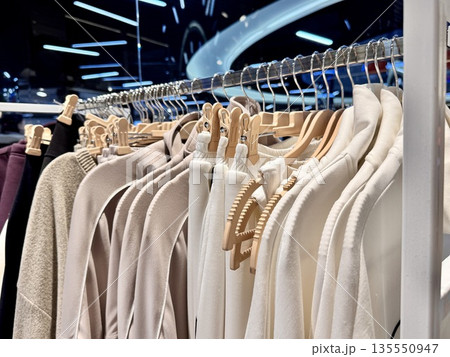 modern multi-colored clothes made of natural fabrics in pastel shades hang on hangers in the store 135550947