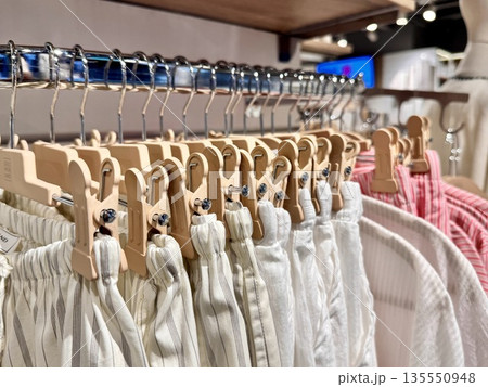 modern multi-colored clothes made of natural fabrics in pastel shades hang on hangers in the store 135550948