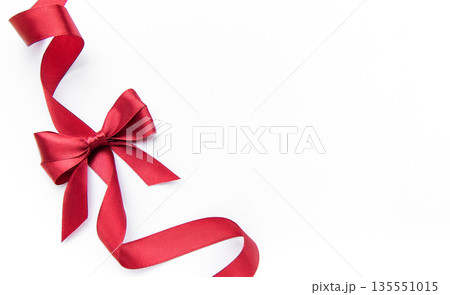 Red satin ribbon forming bow on white background 135551015