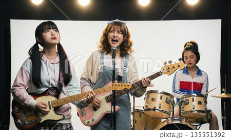 感情を込めて歌い上げるガールズバンドのボーカルと演奏するメンバー 135551392