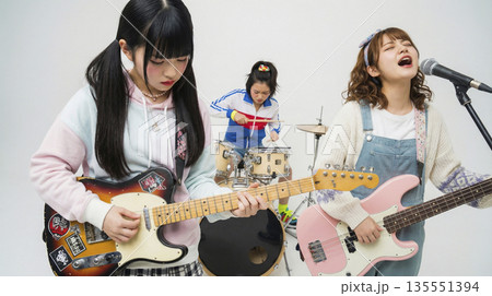 マイクに向かって歌いながら演奏するガールズバンドのボーカルギター 135551394