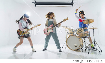 白背景のスタジオで演奏するガールズバンドの全身ショットと照明機材 135551414