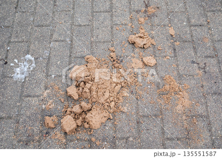 Sand and Debris Scattered on Icy Winter Pedestrian Pavement Surface 135551587