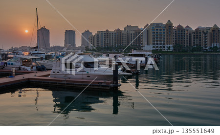 Doha, Qatar- November 15 2025: Porto Arabia Marina in The pearl sunset shot showing luxurious yachts and boats docked at the marina with  residential buildings in background. 135551649