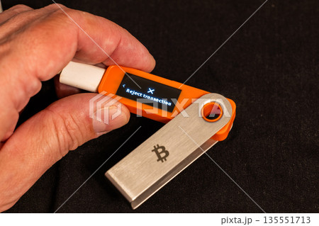 Male hand holding hardware wallet with reject transaction option on its screen Male hand holding hardware wallet with reject transaction option on its screen 135551713
