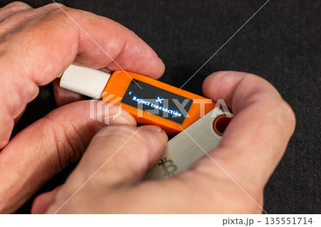 Caucasian man holding hardware wallet with reject transaction message Caucasian man holding hardware wallet with reject transaction message 135551714