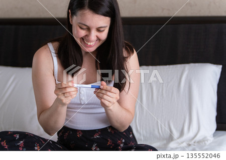Surprised Woman with Positive Pregnancy Test 135552046