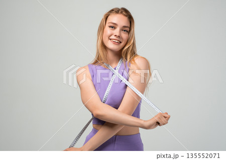 Fit young woman crossing measuring tape on body, fitness goals and weight management concept, healthy lifestyle and self control isolated on neutral background 135552071