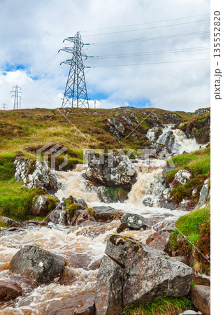 Waterfall stream below electricity pylons in moorland landscape 135552820