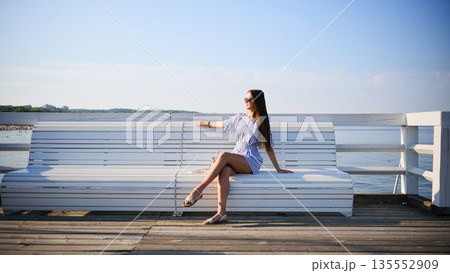 Woman sitting on white bench by the sea in Sopot, Poland Woman sitting on white bench by the sea in Sopot, Poland 135552909