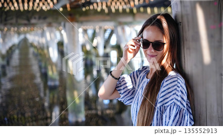 Smiling woman in sunglasses under pier in Sopot Poland 135552913