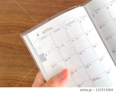 木製テーブルで4月のスケジュール帳を持つ手 木製テーブルで4月のスケジュール帳を持つ手 135553069