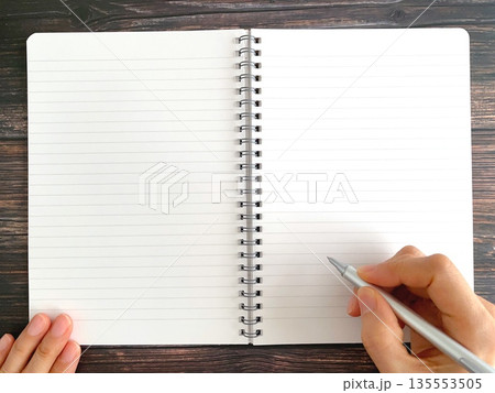 木製テーブルでノートに書く女性の手 135553505