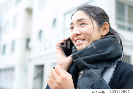 マフラーをしてスマホを使用する女性 135553607