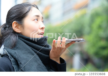 マフラーをしてスマホを使用する女性 135553608
